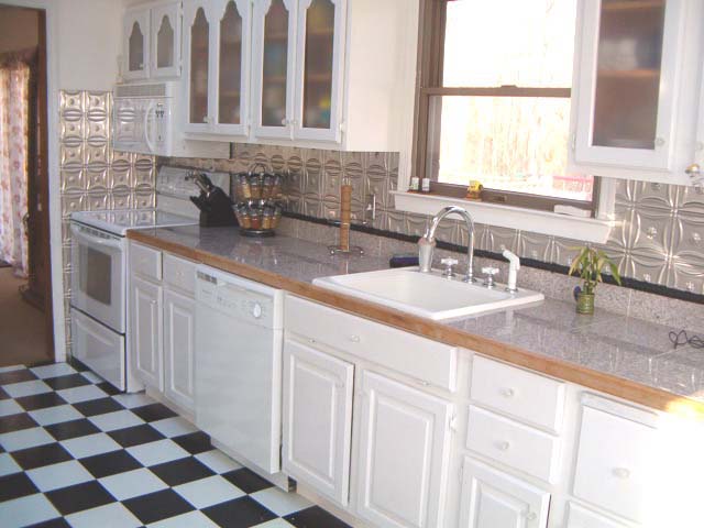 Light wood kitchen cabinets with clear coated aluminum backsplash.