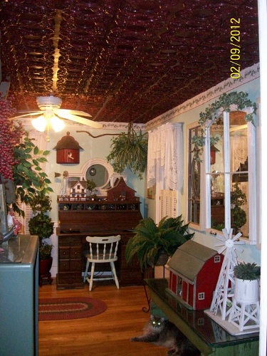 Living room with green walls, light hardwood floors and a big window got a ceiling treatment with our 133 Faux Tin Ceiling Tiles in Rosewood.