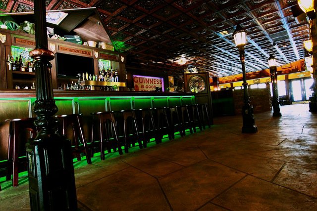 Irish pub and restaurant with rich irish decor, featuring coffered ceiling tiles, lamp posts inside and decorative concrete flooring.