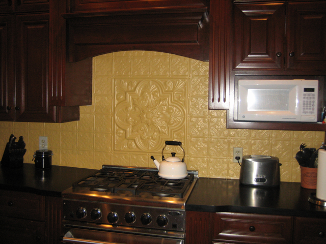 Dark wooden cabinets with creamy, Aluminum backsplash tiles and a medallion as a center piece.