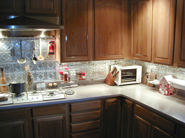 Beautiful kitchen with Dark Cabinets and Diamond Backs stainless steel looking backsplash.