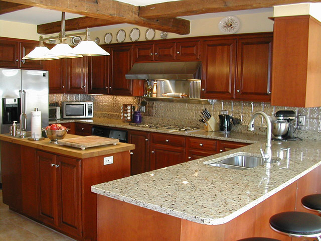 Lovely kitchen with an island, medium dark stained cabinets, Stainless Steel Aplicances and matching backsplash.