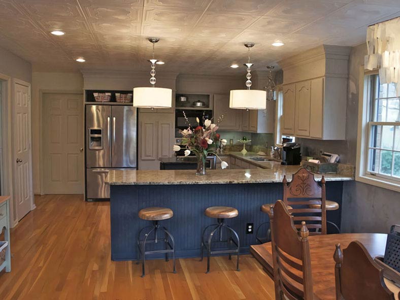 Before shot of a kitchen with dark oak cabinets and popcorn ceiling.