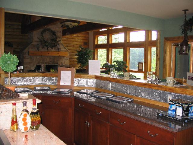 Green walls, natural wooden trim and Aluminum backsplash are the features of this kitchen.