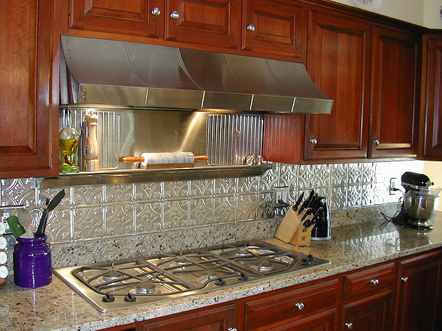 Large Kithen with wooden cabinets, Stainless Steel appliances and a matching metal backsplash.